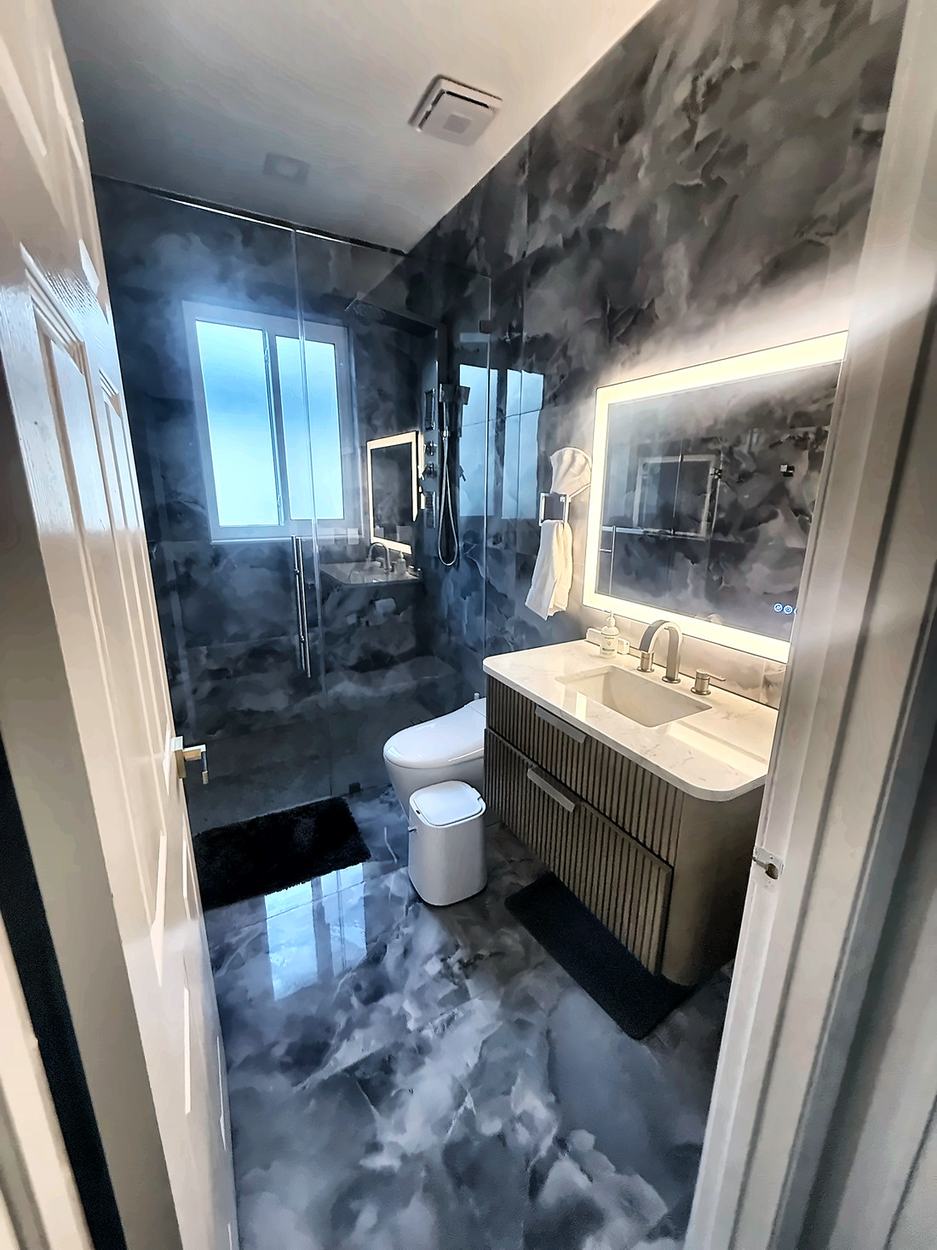 Dark onyx-look bathroom with a curved fluted vanity, marble counter and curbless shower