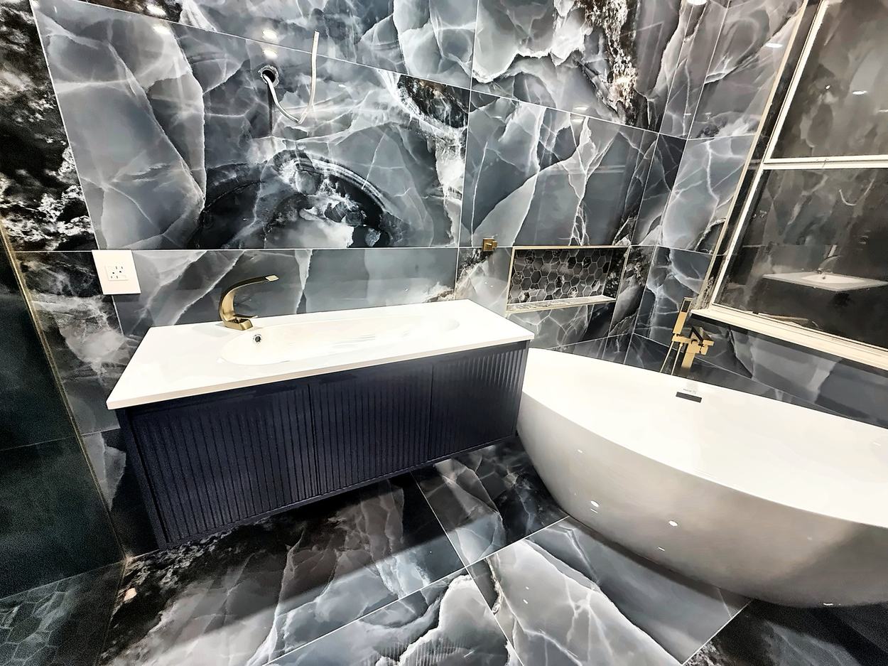 Close view of the onyx primary bath: navy fluted vanity with integrated basin, brass faucet and a hexagon niche