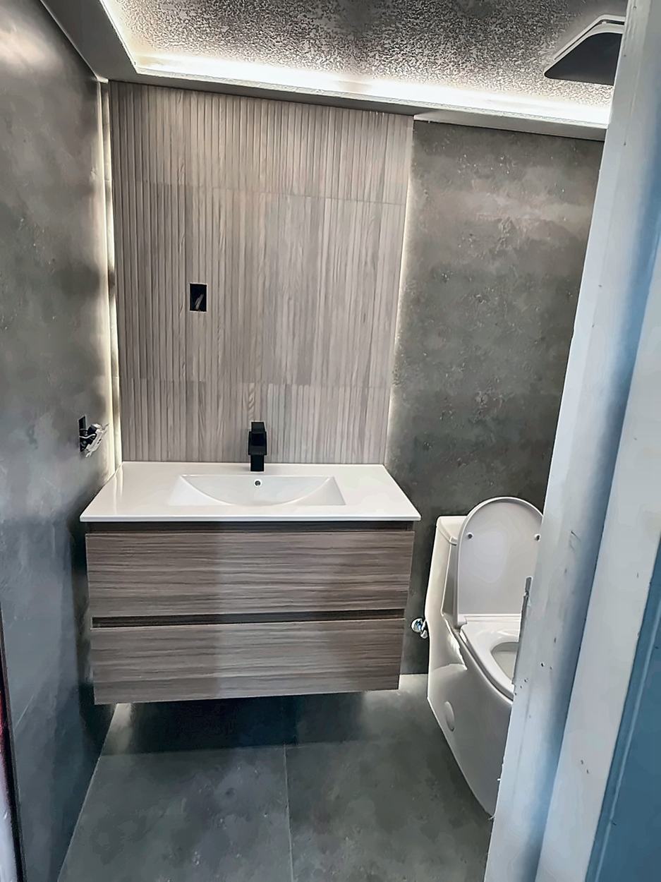 Powder room with a fluted wood-look feature wall, concealed cove light running the ceiling perimeter, floating timber vanity and a matte black tap