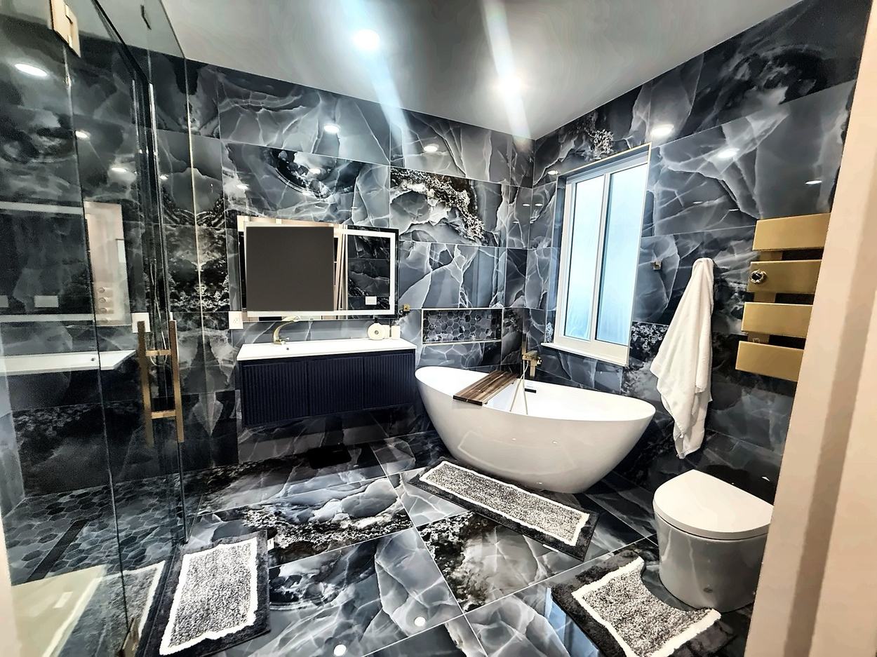 Primary bathroom clad floor to ceiling in blue-grey onyx-look slab with a freestanding tub, navy fluted vanity and brass fittings